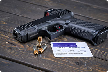 A handgun and a credit card placed on a wooden table.