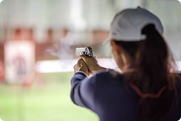 A woman aiming a gun with focused determination.