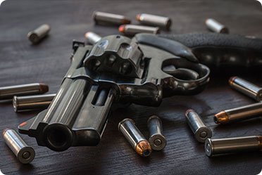 gun and bullets arranged neatly on a wooden table.