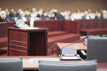 A courtroom with rows of chairs and a microphone.