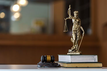 A judge's gavel and a statue of Lady Justice on books, symbolizing justice and the legal profession.