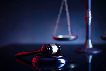 A judge's gavel and scales of justice on a black background, symbolizing fairness and legal proceedings.