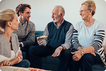 Four people enjoying pizza while sitting on a couch.