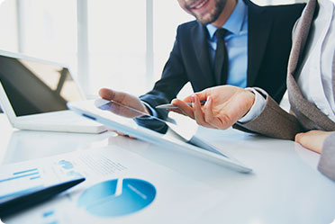 A man and woman in business attire looking at a tablet.