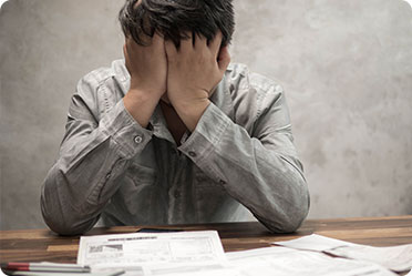 A man sitting with his head in his hands, appearing distressed or overwhelmed.