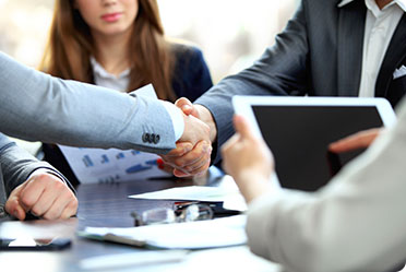 Two business professionals shaking hands in a meeting.