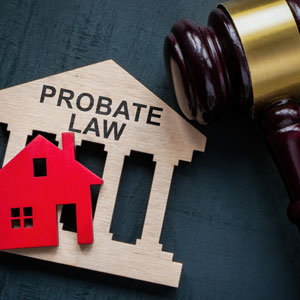 Wooden house cutout labeled 'PROBATE LAW' with a red house and judge's gavel on a dark surface - Alex Kincaid Law